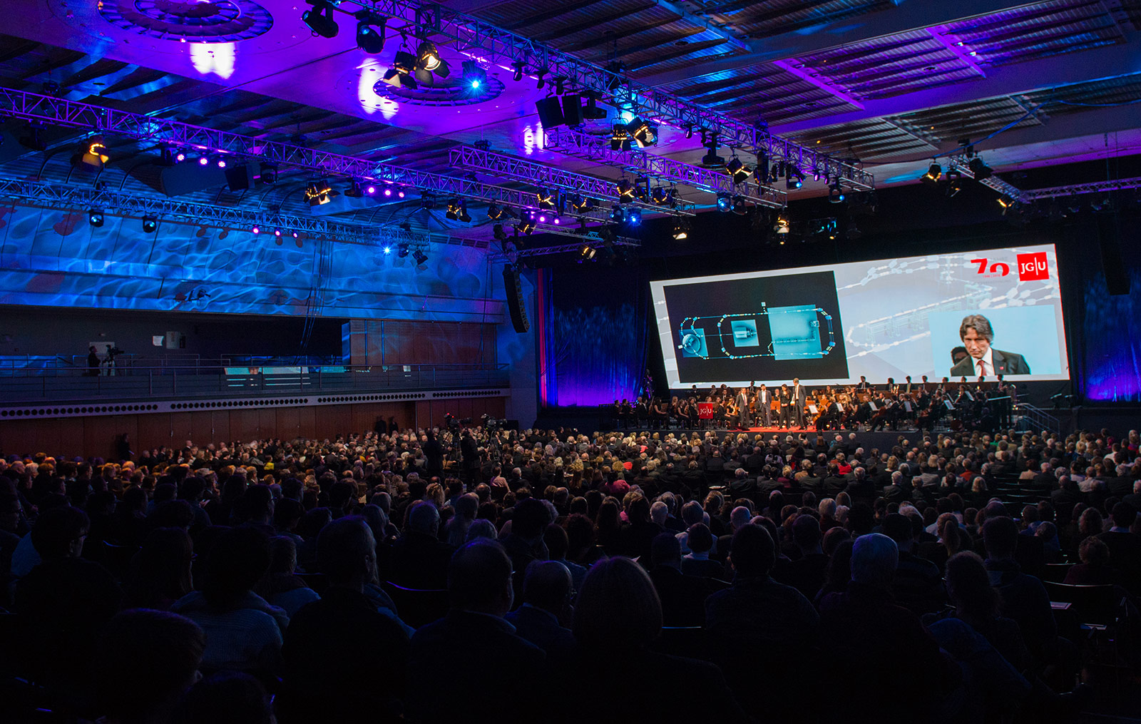 bst: Video Konferenz in großem Saal vor Publikum